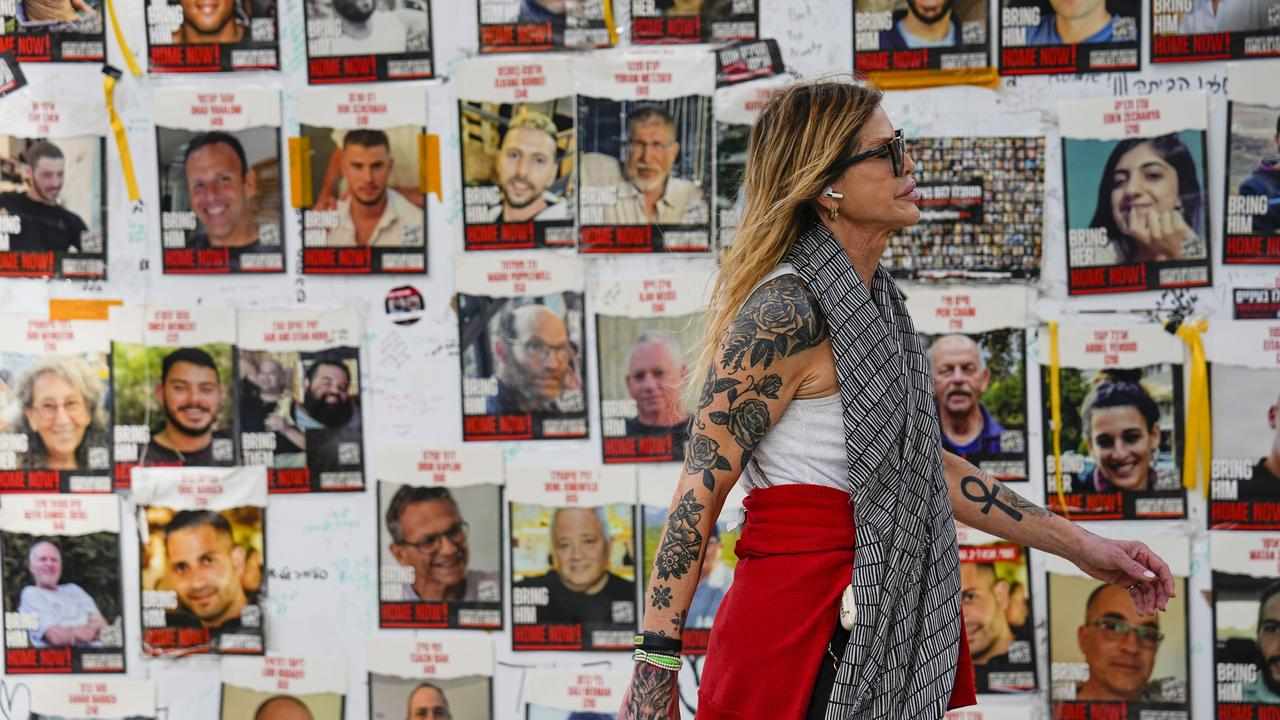 A woman walk past pictures of hostages in Tel Aviv, Israel