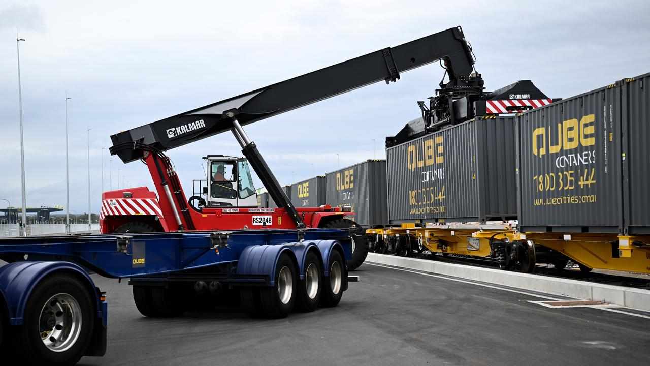 A crane unloads a container from a train.