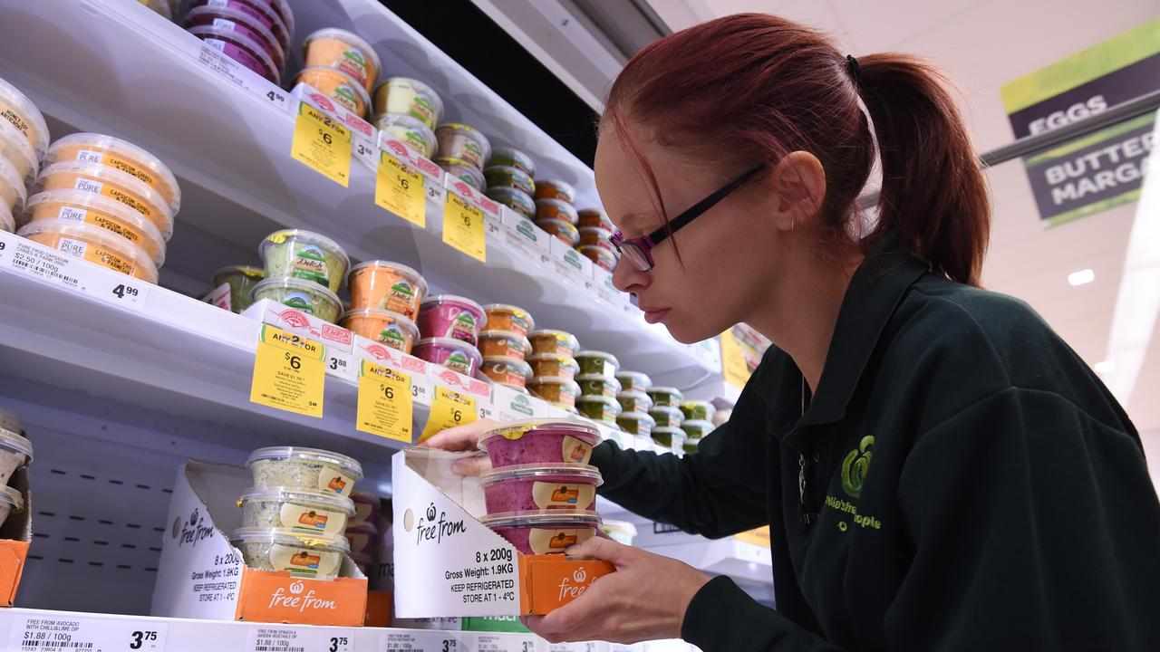 An employee stocking up a fridge in a new Woolworths