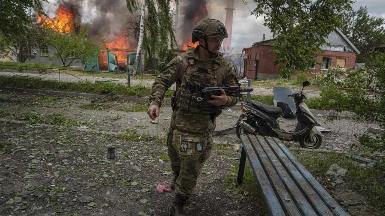 Police officer in front of a burning building in Vovchansk