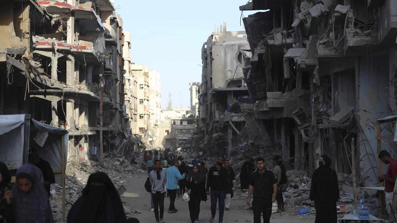 Palestinians walk through debris after Israeli strikes in Khan Younis
