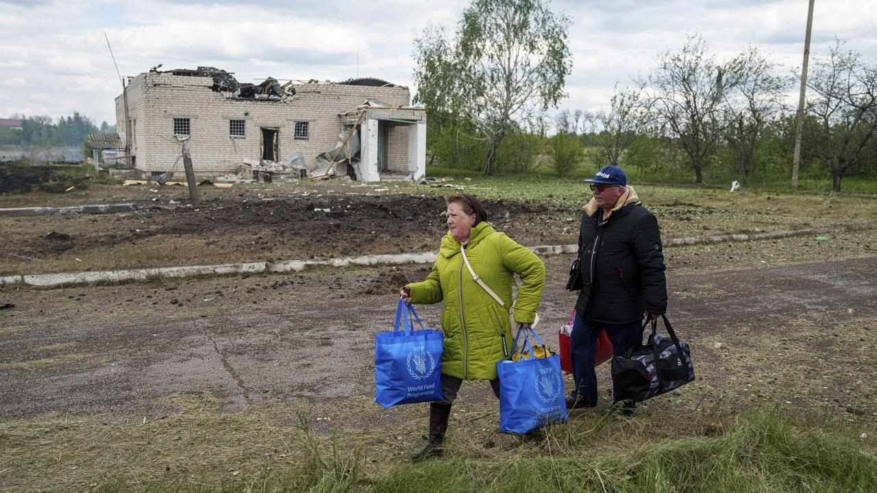People walk with their belongings in Vilcha, near Vovchansk