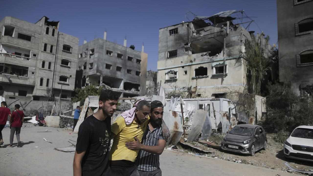 Palestinians help a wounded man after Israeli strikes in Gaza